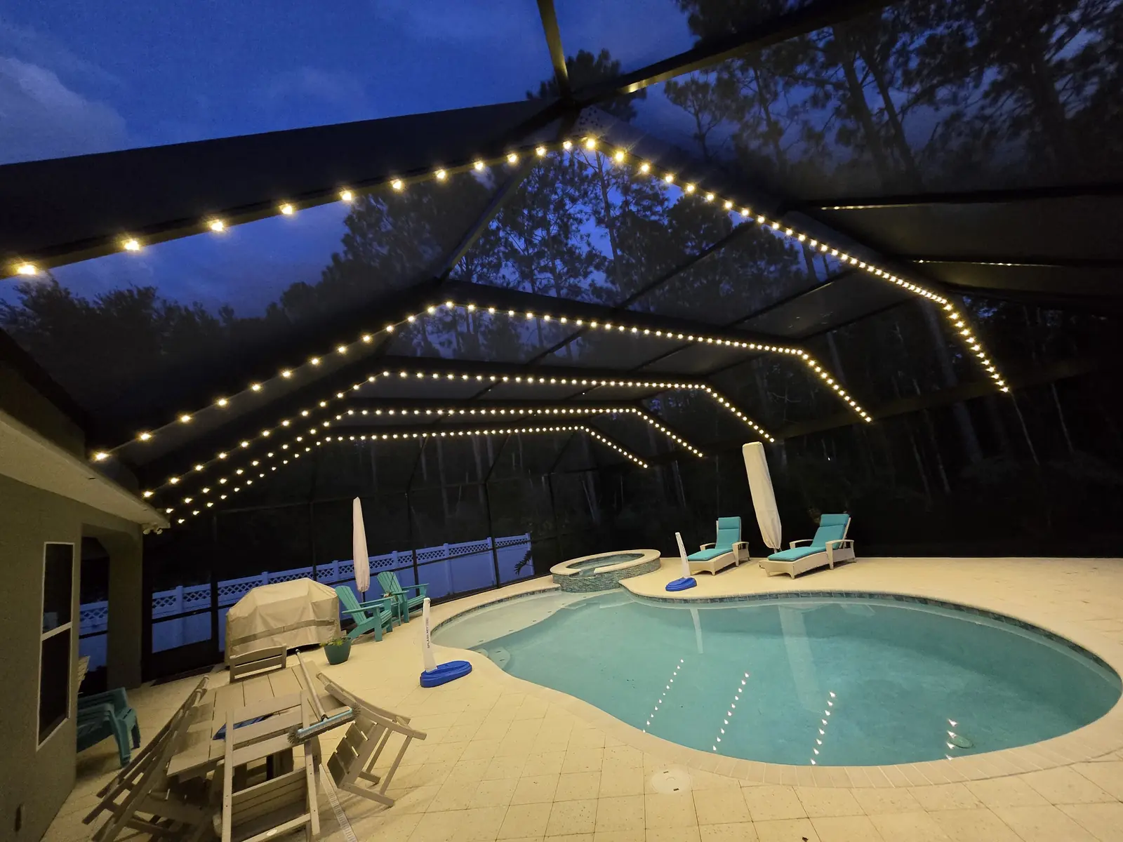 Warm lighting along the main beams of a screened pool enclosure.